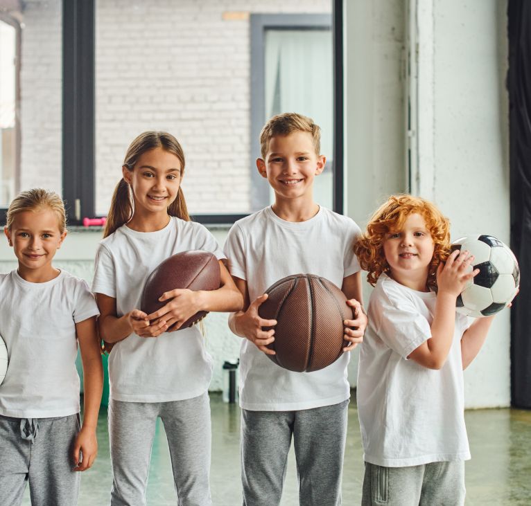 cheerful little children holding different kinds of balls and smiling at camera, child sport