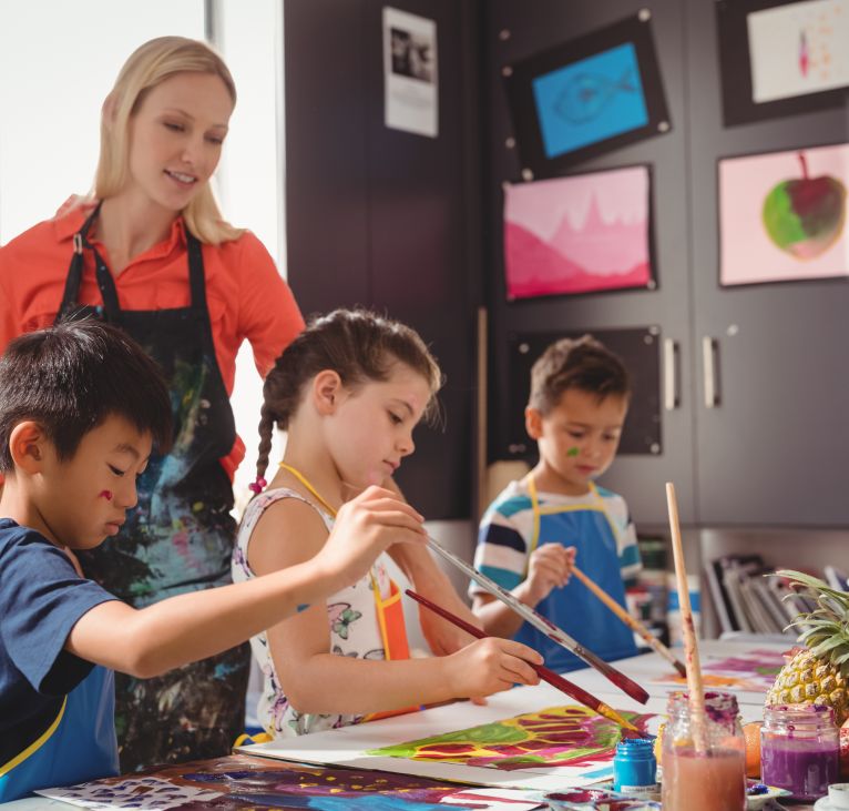 Teacher assisting schoolkids in drawing class at school